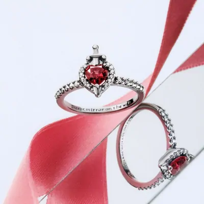 Silver rings with red stones photographed against a ribbon